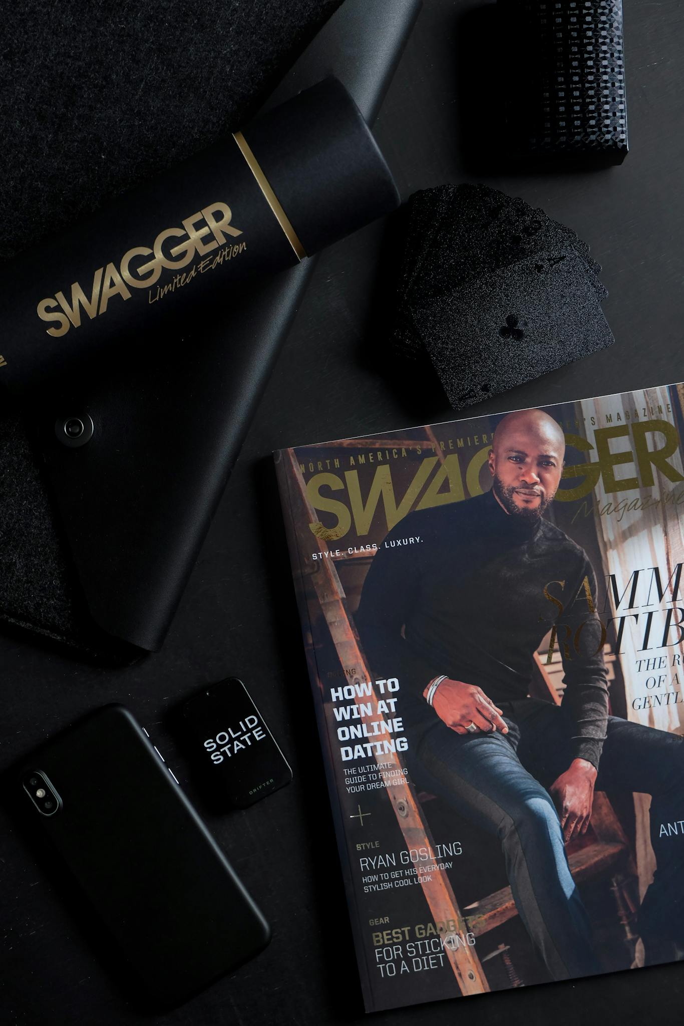 A dark and stylish flat lay featuring a magazine and tech items for a sleek look.